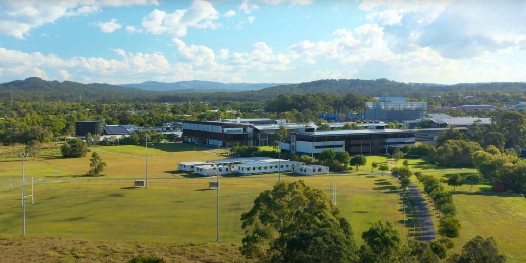 Aerial view of modern University of the Sunshine Coast (UniSC) campus with buildings, sports fields, trees, and surrounding hills, showcasing an educational institution using OSCA composting technology for sustainable organic waste management
