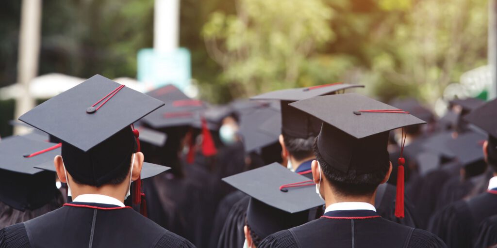 Group of university graduates in black caps and gowns outdoors, representing the education sector where OSCA composter systems provide sustainable organic waste management solutions