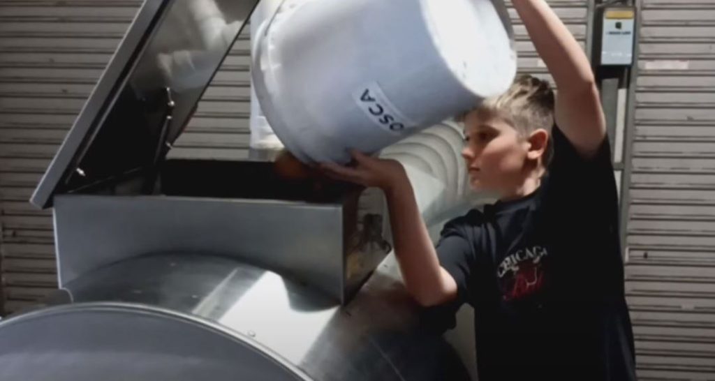 Person loading organic waste into OSCA 75 composter demonstrating ease of use and practical operation of sustainable waste management system